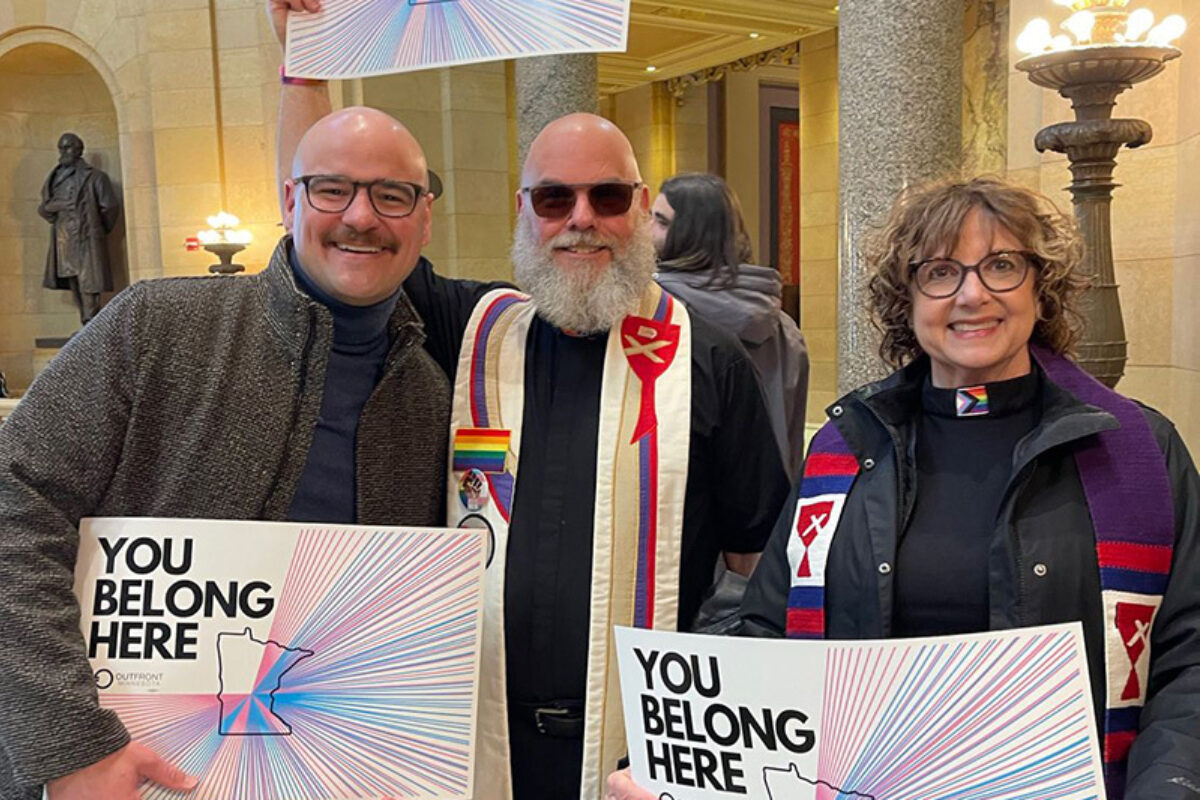 Three leaders in state capitol holding signs saying 'You belong here'